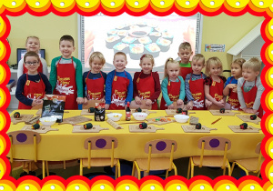Na zdjęciu grupa dzieci w czerwonych fartuchach kucharzy.